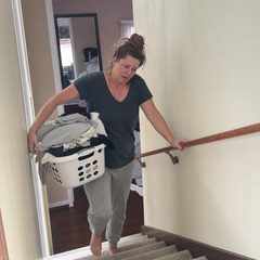 Donna che porta una cesta del bucato su per le scale