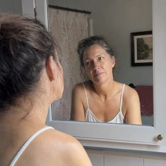 Donna che si guarda pensierosa allo specchio