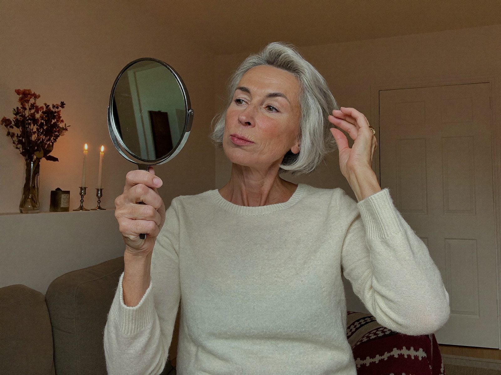Vrouw kijkt kritisch in een handspiegel naar haar huid en haar